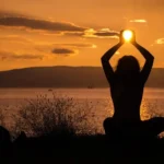 A serene nature scene with a woman meditating featuring Holistic Health & Well-Being