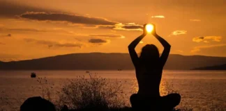 A serene nature scene with a woman meditating featuring Holistic Health & Well-Being