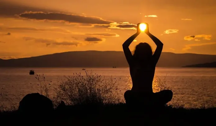 A serene nature scene with a woman meditating featuring Holistic Health & Well-Being