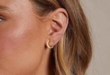 A pair of elegant small gold hoop earrings displayed on a white marble surface