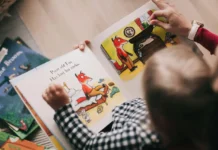A joyful preschool teacher reading a colorful picture book to a diverse group of attentive toddlers in a cozy classroom reading nook featuring early literacy