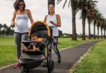 Professional lifestyle photo of an athletic mother in premium activewear jogging through an upscale urban park with a sleek, modern Jogging Stroller Pish Posh Baby