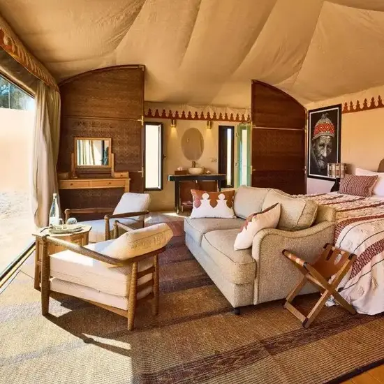 Luxury desert camp in Morocco glowing at sunset among Sahara sand dunes